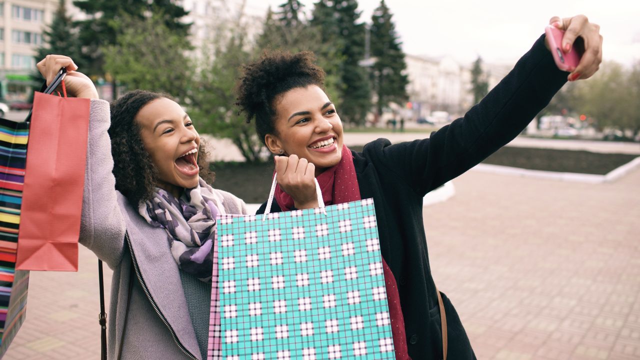 Two happy shoppers taking a selfie with their shopping bags